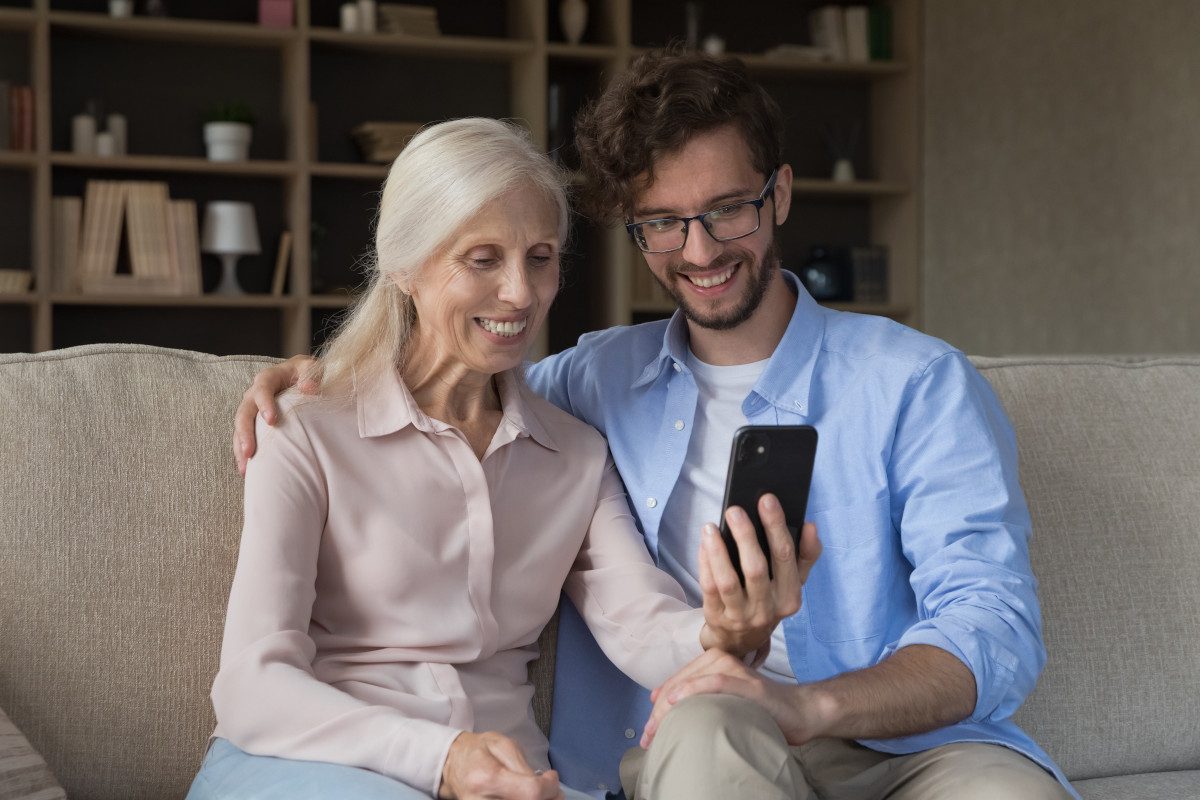 An older person sitting comfortably in an armchair, at ease using their phone.